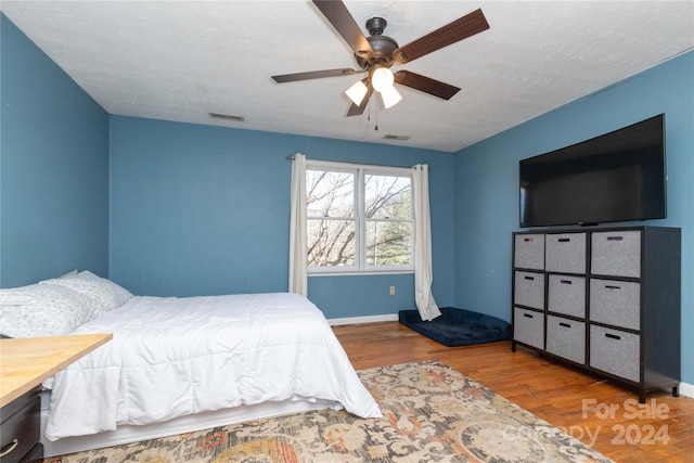 bedroom featuring hardwood / wood-style floors, a textured ceiling, and ceiling fan