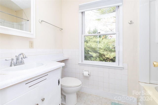 bathroom featuring tile patterned flooring, vanity, toilet, and tile walls