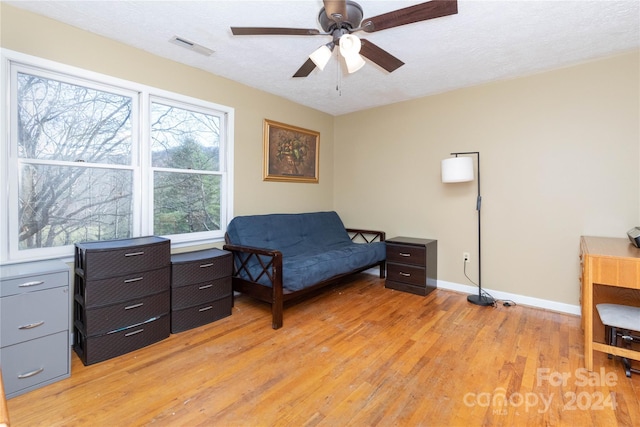 bedroom with ceiling fan, a textured ceiling, and light hardwood / wood-style flooring