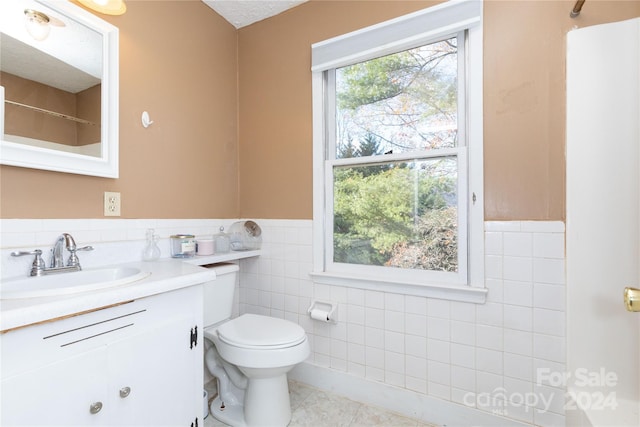 bathroom with tile patterned flooring, vanity, a healthy amount of sunlight, and tile walls