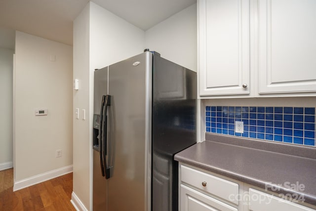 kitchen featuring white cabinets, stainless steel fridge, dark hardwood / wood-style floors, and decorative backsplash