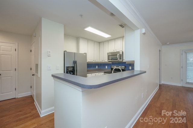 kitchen with kitchen peninsula, stainless steel appliances, white cabinetry, and light hardwood / wood-style flooring