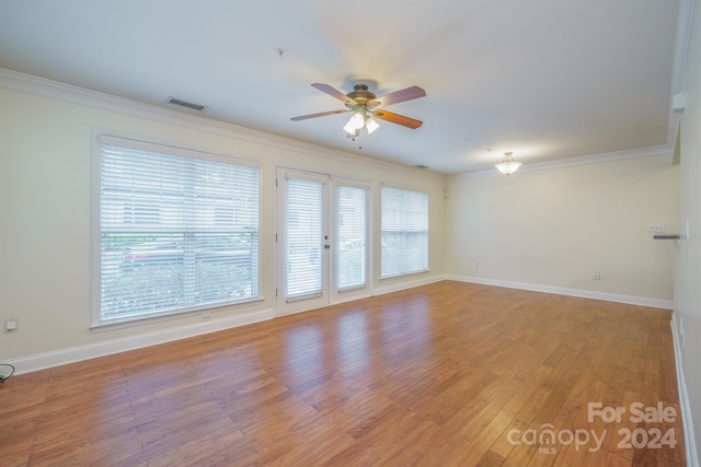 empty room featuring plenty of natural light, light wood-type flooring, and ornamental molding