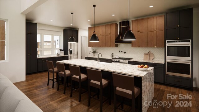 kitchen with decorative backsplash, dark hardwood / wood-style flooring, a kitchen island with sink, and decorative light fixtures