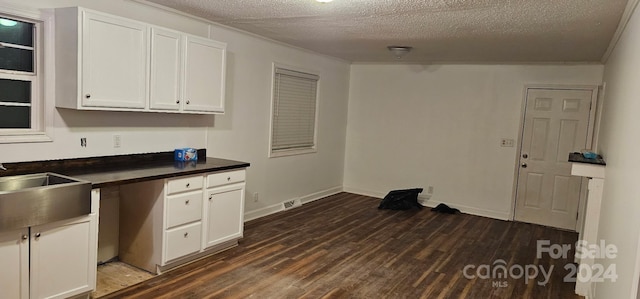 kitchen featuring white cabinetry, dark hardwood / wood-style floors, a textured ceiling, and ornamental molding