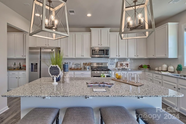 kitchen featuring appliances with stainless steel finishes, dark hardwood / wood-style flooring, pendant lighting, and a breakfast bar area