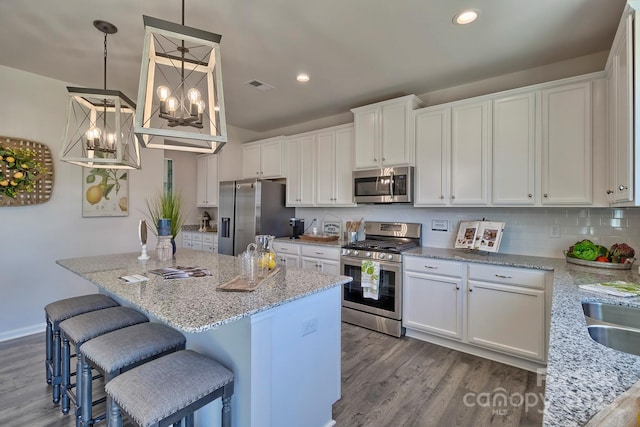 kitchen with pendant lighting, stainless steel appliances, and a kitchen island with sink