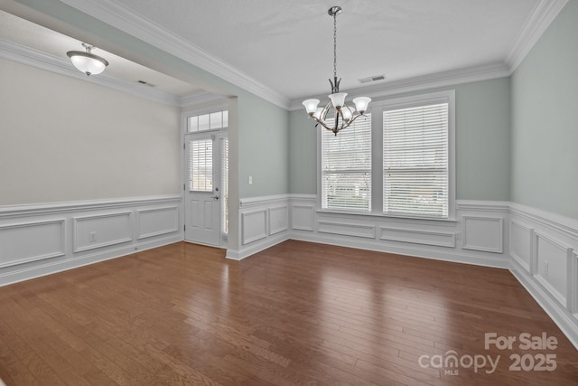 unfurnished dining area with wood-type flooring, a chandelier, and ornamental molding