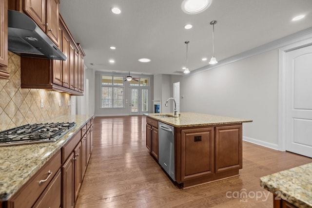 kitchen with a kitchen island with sink, sink, hanging light fixtures, decorative backsplash, and stainless steel appliances