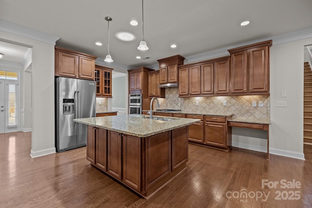 kitchen featuring appliances with stainless steel finishes, a center island with sink, light stone counters, and crown molding