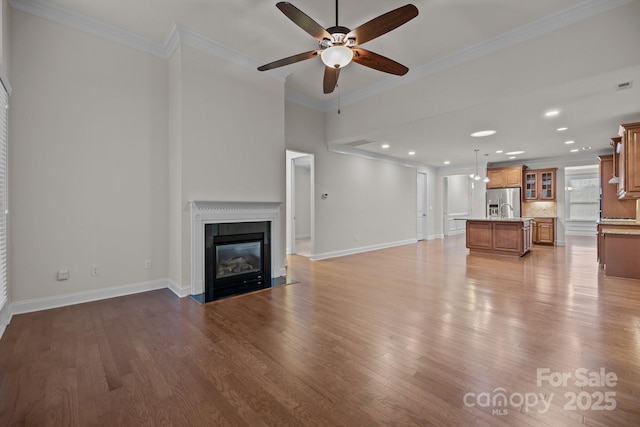 unfurnished living room featuring ceiling fan, light wood-type flooring, and crown molding