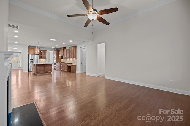 unfurnished living room featuring ceiling fan, crown molding, sink, wood-type flooring, and a fireplace