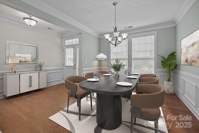 dining room featuring hardwood / wood-style floors, an inviting chandelier, and crown molding