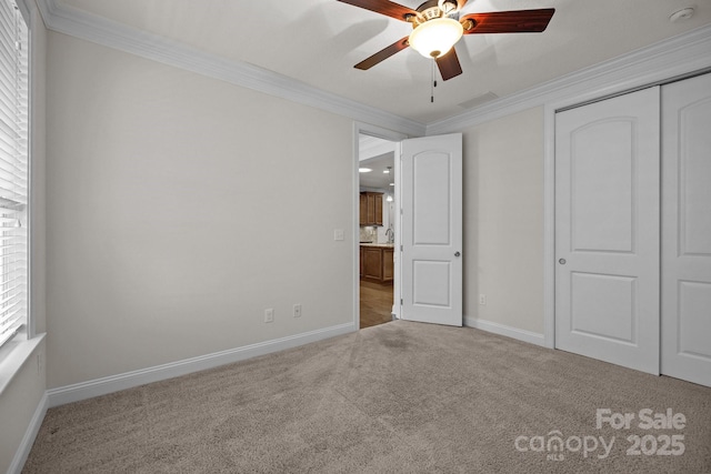 unfurnished bedroom featuring carpet flooring, a closet, ceiling fan, and crown molding