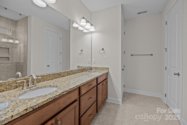 bathroom featuring tile patterned flooring, vanity, and tiled shower