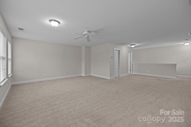 empty room featuring light carpet, a textured ceiling, and a wealth of natural light