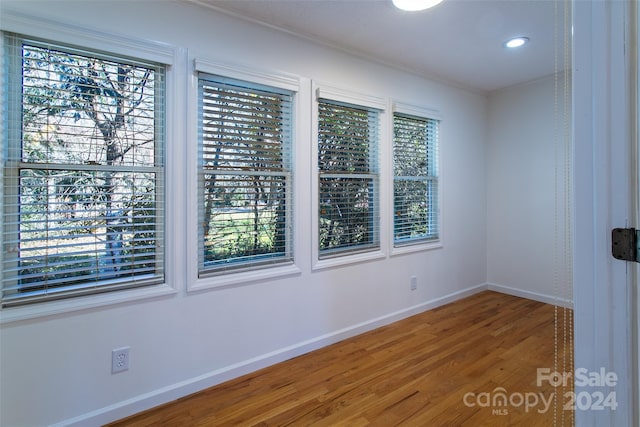 empty room with plenty of natural light and hardwood / wood-style floors