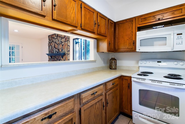 kitchen featuring plenty of natural light, light tile patterned floors, and white appliances