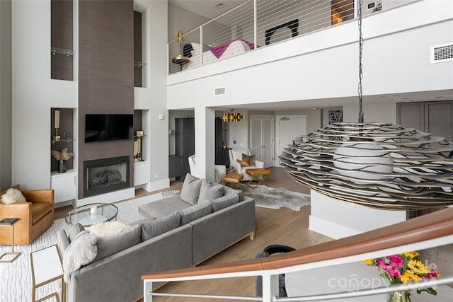 living room featuring hardwood / wood-style flooring, a notable chandelier, and a high ceiling