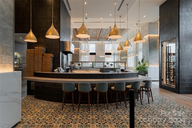 bar with hardwood / wood-style floors, hanging light fixtures, and tile walls