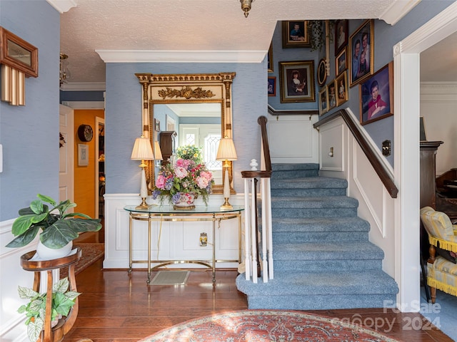 stairs featuring a textured ceiling, hardwood / wood-style flooring, and ornamental molding