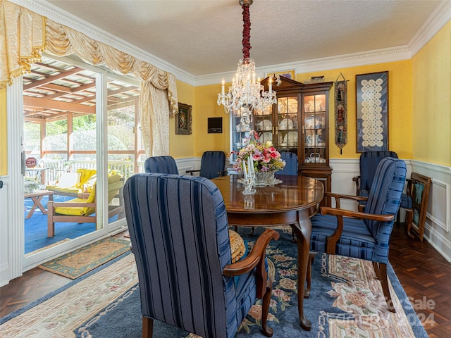 dining room with dark parquet flooring, crown molding, a textured ceiling, and an inviting chandelier