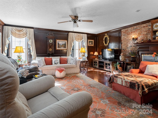 living room with a textured ceiling, dark hardwood / wood-style flooring, ceiling fan, and crown molding