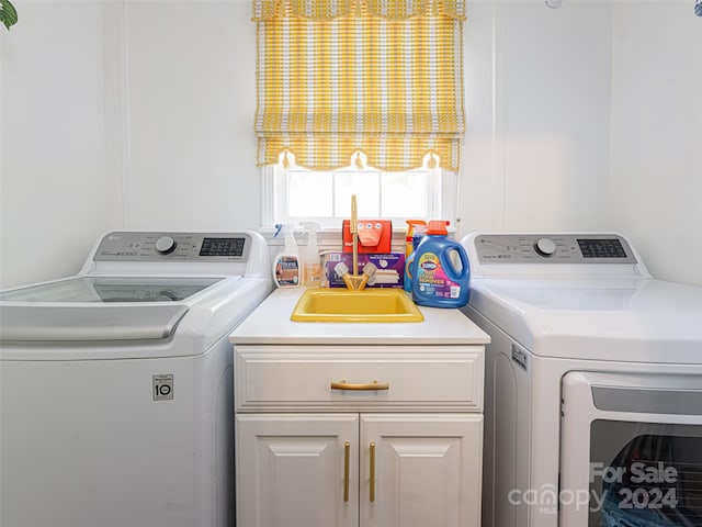 clothes washing area featuring washer and clothes dryer and cabinets