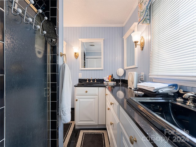 bathroom featuring a tile shower, tile patterned floors, a textured ceiling, vanity, and ornamental molding