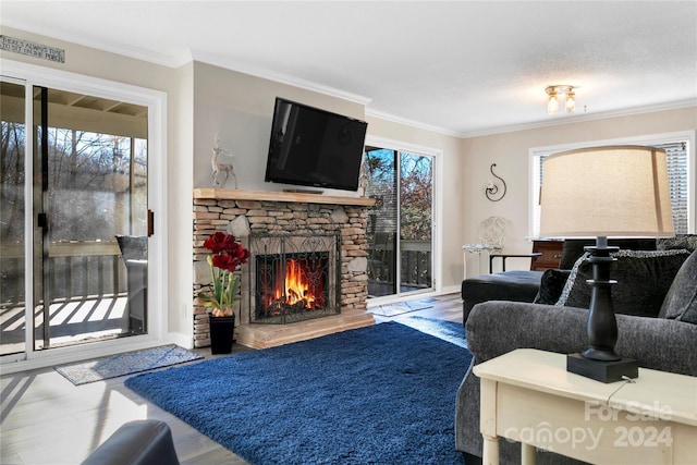 living room featuring hardwood / wood-style flooring, a stone fireplace, a wealth of natural light, and crown molding