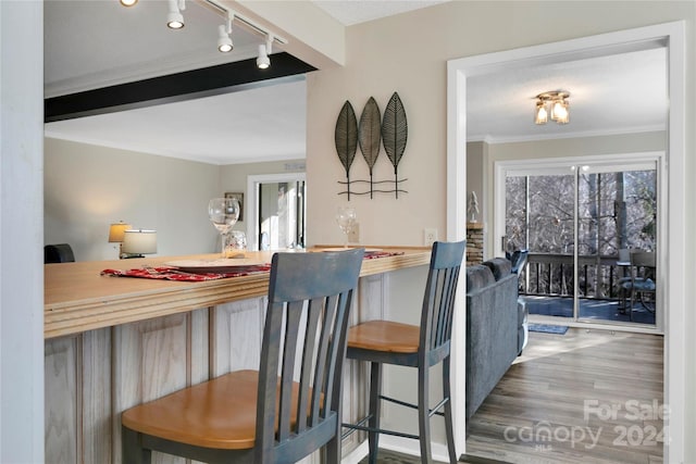 kitchen with plenty of natural light, wood-type flooring, crown molding, and a breakfast bar area