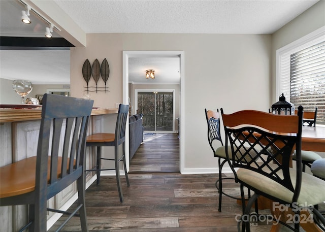 dining space with a textured ceiling, dark hardwood / wood-style flooring, and rail lighting