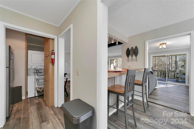 kitchen with rail lighting, stainless steel fridge, ornamental molding, a textured ceiling, and wood-type flooring