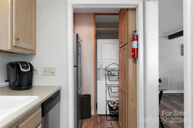 kitchen featuring stainless steel appliances, dark wood-type flooring, stacked washing maching and dryer, a textured ceiling, and light brown cabinetry