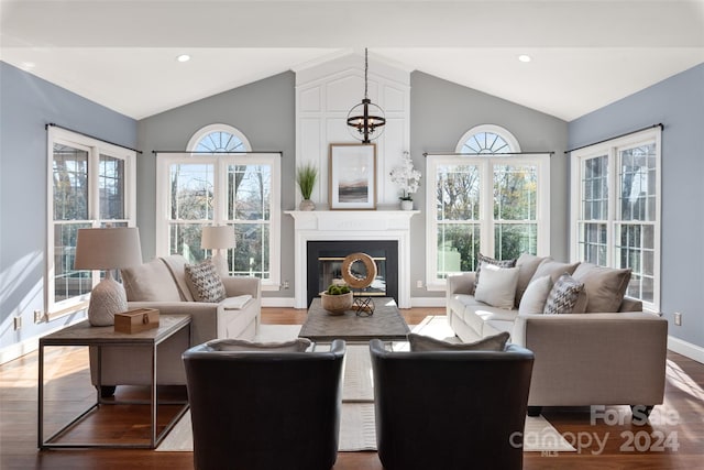 living room with hardwood / wood-style floors, lofted ceiling, and a notable chandelier