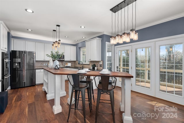 kitchen with pendant lighting, dark wood-type flooring, wooden counters, appliances with stainless steel finishes, and white cabinetry