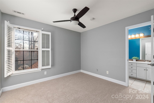 unfurnished bedroom with light carpet, ensuite bathroom, ceiling fan, and sink