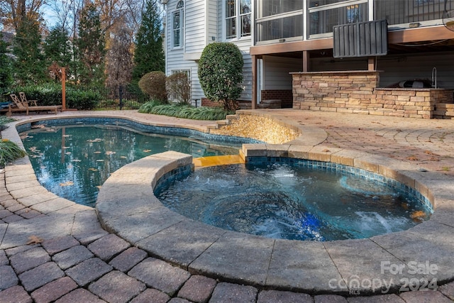 view of swimming pool with an in ground hot tub, a patio area, and a sunroom