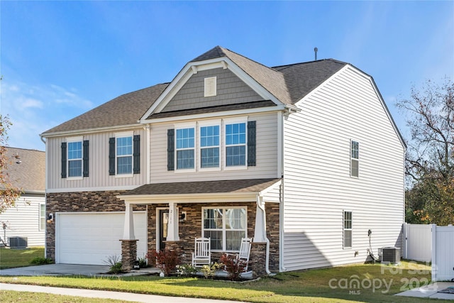 craftsman-style home with covered porch, a garage, central AC, and a front lawn