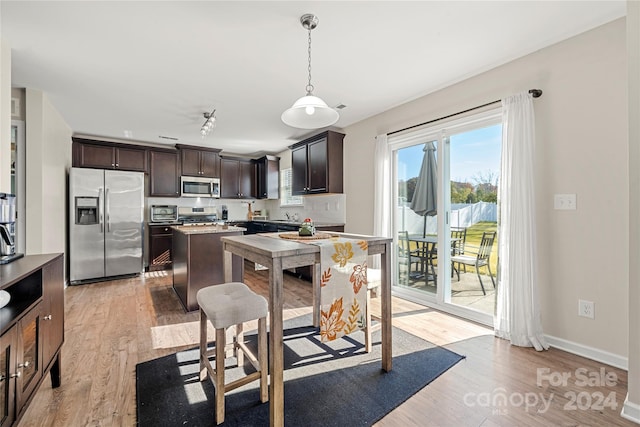 kitchen with pendant lighting, a breakfast bar, light hardwood / wood-style flooring, dark brown cabinetry, and stainless steel appliances