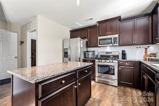 kitchen with a center island, light stone countertops, light wood-type flooring, and stainless steel appliances