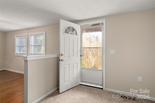 entryway with a textured ceiling and light hardwood / wood-style flooring