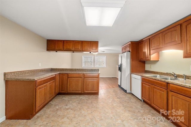 kitchen featuring kitchen peninsula, light wood-type flooring, white appliances, and sink