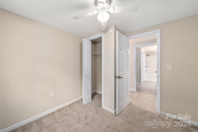 unfurnished bedroom with light carpet, a closet, and ceiling fan