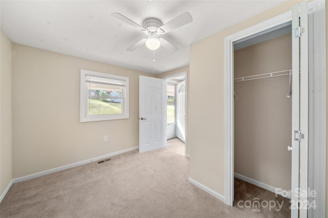 unfurnished bedroom featuring a closet, light colored carpet, and ceiling fan