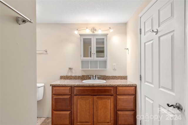 bathroom with vanity, toilet, and a textured ceiling