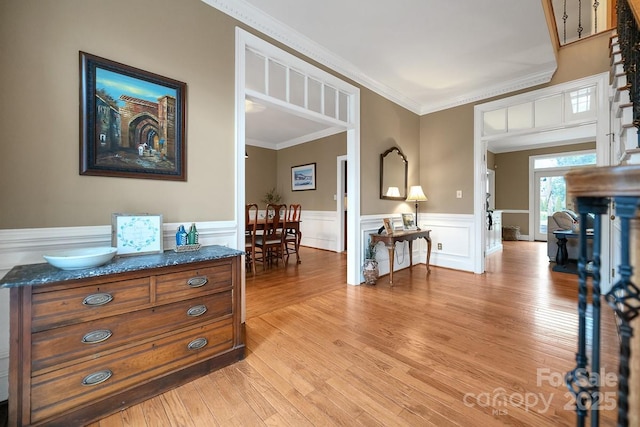 interior space with ornamental molding, wainscoting, and light wood-style flooring