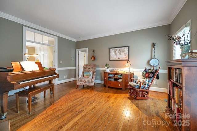 sitting room with baseboards, ornamental molding, and wood finished floors