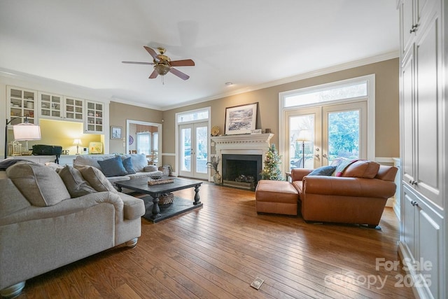 living area featuring a healthy amount of sunlight, ornamental molding, wood finished floors, and french doors