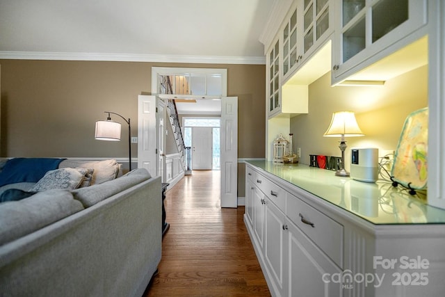 kitchen featuring glass insert cabinets, ornamental molding, wood finished floors, light countertops, and white cabinetry